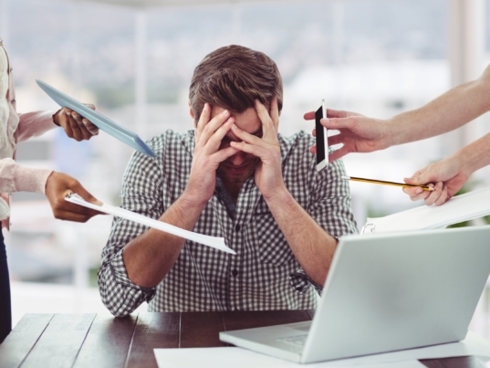 Stressed man frustrated with electronic devices in office